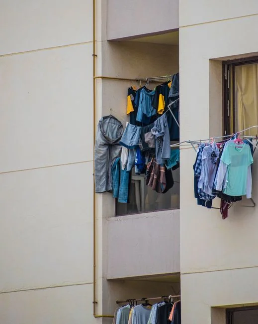 Deux femmes de ménage en uniforme refaisant le lit d’une chambre d’hôtel avec du linge propre et des oreillers.